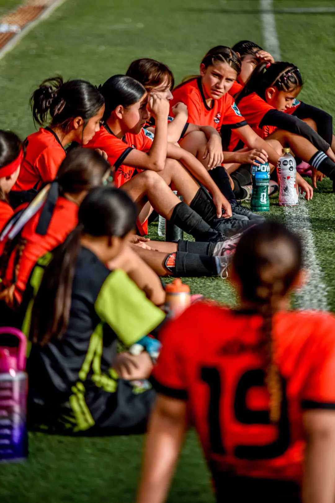 Girls soccer team sitting together on the sideline